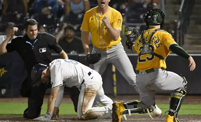 Tampa Bay Rays' Brandon Lowe (8) reacts after being tagged out at home by Athletics catcher Shea Langeliers (23) during the eighth inning of a baseball game Monday, June 30, 2025, in Tampa, Fla. (AP Photo/Jason Behnken)