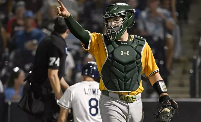 Athletics catcher Shea Langeliers, front, celebrates after tagging out Tampa Bay Rays' Brandon Lowe (8) at home during the eighth inning of a baseball game Monday, June 30, 2025, in Tampa, Fla. (AP Photo/Jason Behnken)