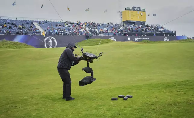A technician changes the camera batteries on spidercam on the 18th green during the first round of the British Open golf championship at the Royal Portrush Golf Club, Northern Ireland, Thursday, July 17, 2025. (AP Photo/Jon Super)