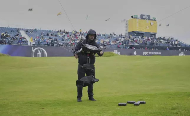 A technician changes the camera batteries on spidercam on the 18th green during the first round of the British Open golf championship at the Royal Portrush Golf Club, Northern Ireland, Thursday, July 17, 2025. (AP Photo/Jon Super)