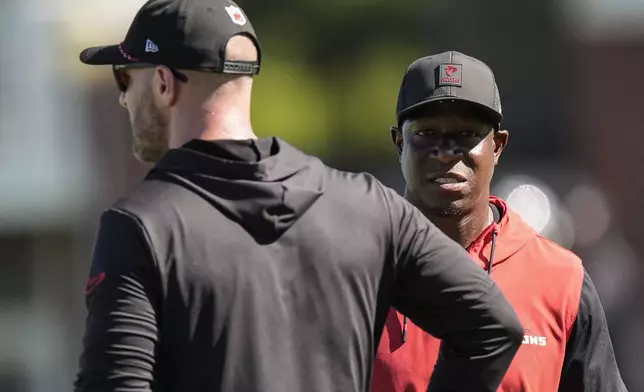 Atlanta Falcons head coach Raheem Morris, right, speaks with coach T. J. Lang during a Atlanta Falcons training camp, Saturday, July 26, 2025, in Flowery Branch. (AP Photo/Mike Stewart)
