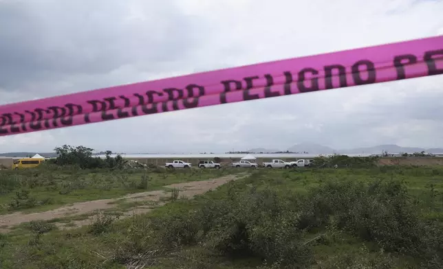 Danger warning tape streches along a Nextipac ranch where prosecutors say bodies were discovered in a mass grave during excavations for the construction, in the Zapopan municipality, Jalisco state, Mexico, Friday, July 11, 2025. (AP Photo/Alejandra Leyva)