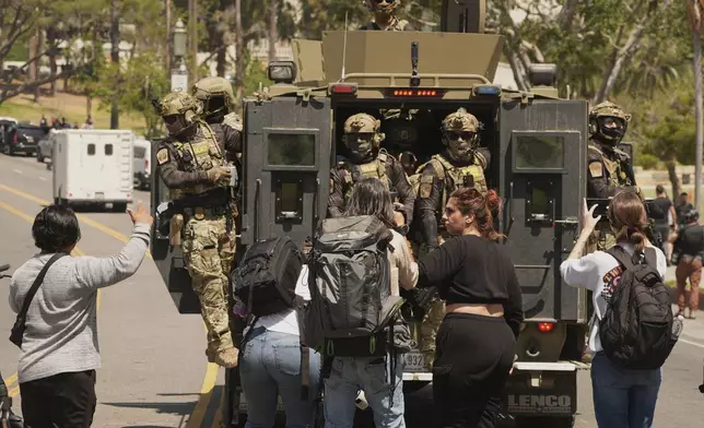 Federal agents ride on and armored vehicle at MacArthur Park Monday, July 7, 2025, in Los Angeles. (AP Photo/Damian Dovarganes)