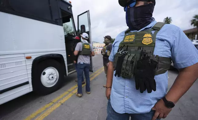 A Border Patrol agent looks on as a family from Colombia is detained and escorted to a bus by federal agents following an appearance at immigration court Monday, July 14, 2025, in San Antonio. (AP Photo/Eric Gay)