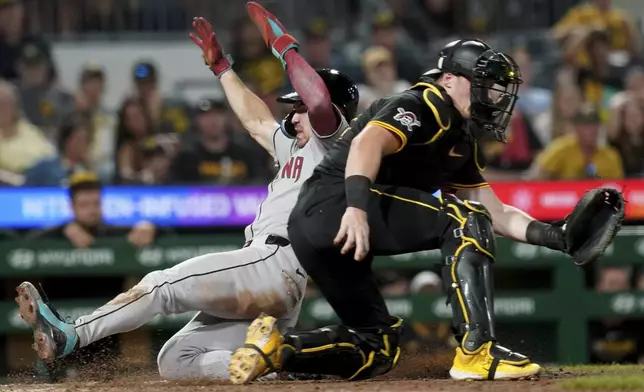 Arizona Diamondbacks' Corbin Carroll, left, scores as Pittsburgh Pirates catcher Henry Davis waits for the late throw during the eleventh inning of a baseball game, Friday, July 25, 2025, in Pittsburgh. (AP Photo/Matt Freed)