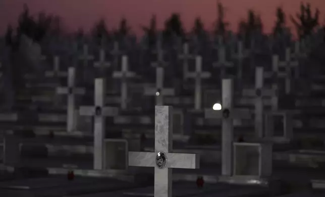 The portraits of a Greek Cypriot soldiers killed in the 1974 Turkish invasion in Cyprus are seen on the crosses on their graves at the Tymvos Macedonitissas military cemetery in the divided capital of Nicosia, Saturday, July 19, 2025. (AP Photo/Petros Karadjias)