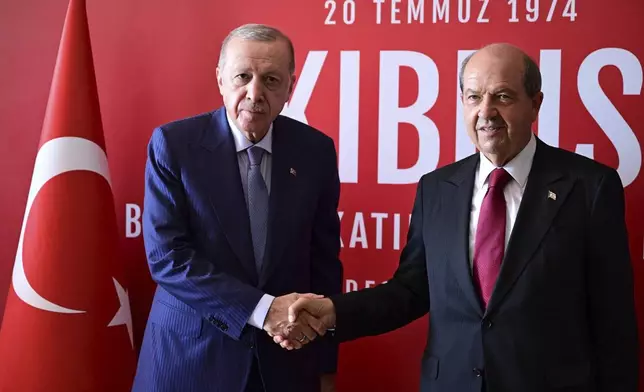 Turkish President Recep Tayyip Erdogan, left, and the Turkish Cypriot leader Ersin Tatar shake hands during their meeting before a military parade marking the 51st anniversary of the 1974 Turkish invasion in the Turkish occupied area of the divided capital Nicosia, Cyprus, in the divided capital of Nicosia, Sunday, July 20, 2025. (AP Photo/Nedim Enginsoy)