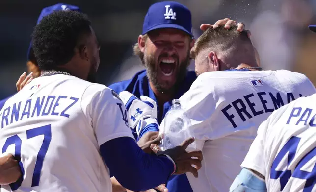 Los Angeles Dodgers' Freddie Freeman, right, celebrates with Teoscar Hernández, left, and Clayton Kershaw after hitting a walk-off single during the ninth inning of a baseball game against the Minnesota Twins, Wednesday, July 23, 2025, in Los Angeles. (AP Photo/Mark J. Terrill)