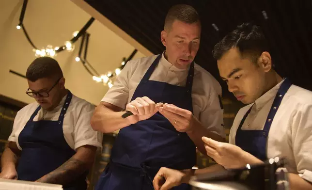 Executive chef Torsten Vildgaard, center, and his staff chop nuts at FZN Restaurant on Palm Jumeirah in Dubai, United Arab Emirates, Friday, June 13, 2025. (AP Photo/ Fatima Shbair)