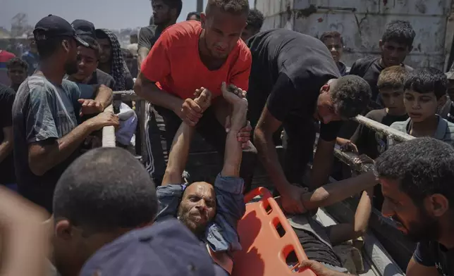 Injured Palestinians are transferred to an ambulance after being wounded while waiting for aid arriving from the northern Gaza Strip, in Gaza City, Tuesday, July 22, 2025. (AP Photo/Jehad Alshrafi)
