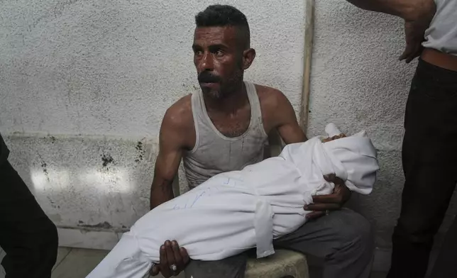 A Palestinian man carries the body of a child killed in an Israeli airstrike on Gaza, at Shifa Hospital in Gaza City, Tuesday, July 22, 2025. (AP Photo/Jehad Alshrafi)