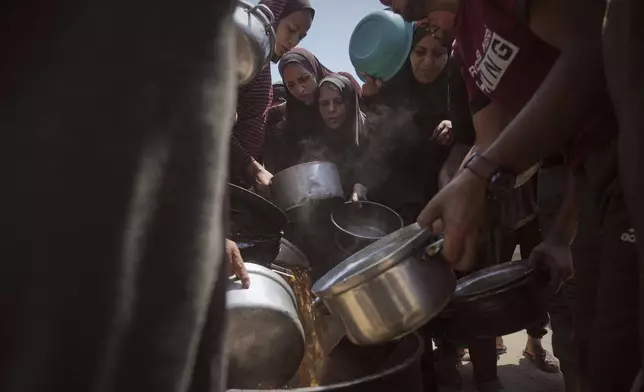 Displaced Palestinians receive donated food at a community kitchen in Gaza City, northern Gaza Strip, Tuesday, July 22, 2025. (AP Photo/Jehad Alshrafi)