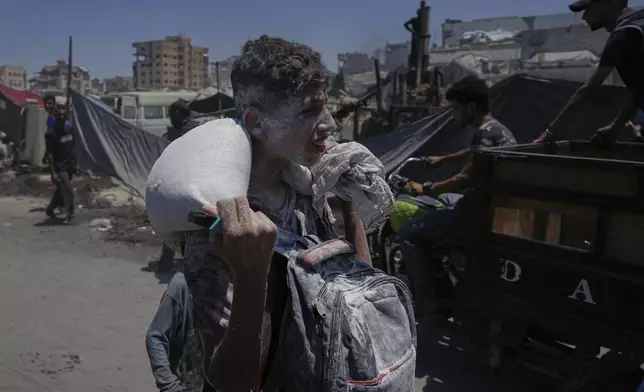 Palestinians carry sacks of flour unloaded from a humanitarian aid convoy that reached Gaza City from the northern Gaza Strip, Tuesday, July 22, 2025. (AP Photo/Jehad Alshrafi)