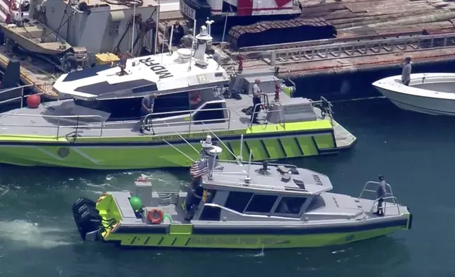 This image taken from video provided by WSVN-TV shows Miami-Dade Fire Rescue and others in boats around what appears to be a barge involved in an accident with a group of kids and an adult on a sailing boat during a sailing camp, Monday, July 28, 2025, in Miami. (WSVN-TV via AP)