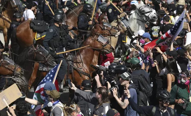FILE - Demonstrators standoff against law enforcement on horseback during a protest, June 14, 2025, in Los Angeles. (AP Photo/Ethan Swope, fle)