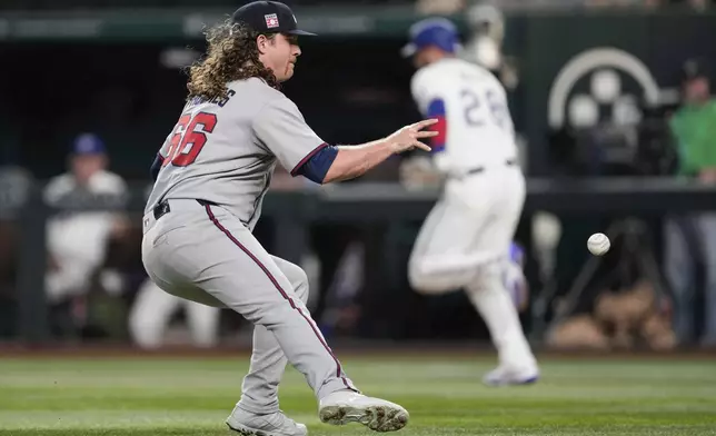 Atlanta Braves starting pitcher Grant Holmes, left, fields a bunt before throwing out Texas Rangers' Jonah Heim, back right, at first base in the second inning of a baseball game Saturday, July 26, 2025, in Arlington, Texas. (AP Photo/Tony Gutierrez)