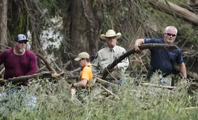 Law enforcement assist during clean-up efforts after flooding in Center Point, Texas, Monday, July 7, 2025. (AP Photo/Ashley Landis)