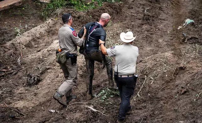 A Texas Department of Public Safety Trooper and Kerr County Sheriff's deputy assist a rescue diver out of the water at a search and rescue site along the Guadalupe River after a flash flood swept through the area, Monday, July 7, 2025, in Ingram, Texas. (AP Photo/Eli Hartman)