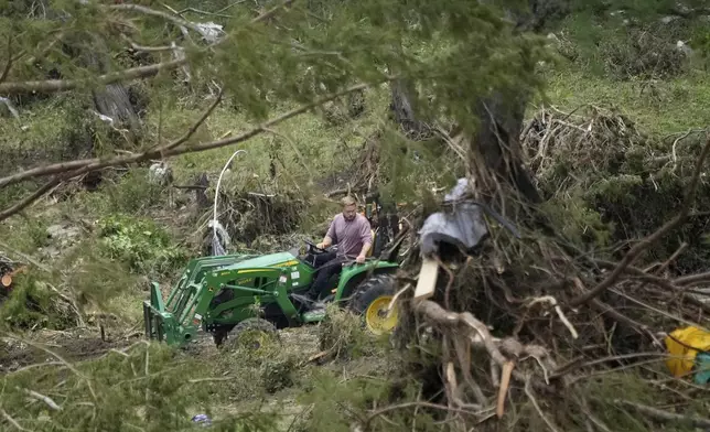 A person drives a tractor as they clean-up along the river after flooding in Kerrville, Texas, Monday, July 7, 2025. (AP Photo/Ashley Landis)