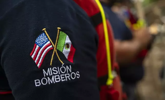 Firefighters from Ciudad Acuna, Mexico, gather for a briefing as they aid in search and rescue efforts near the Guadalupe River after a flash flood swept through the area Monday, July 7, 2025, in Ingram, Texas. (AP Photo/Eli Hartman)