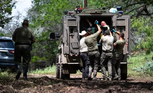 Texas Department of Public Safety Troopers load a recovered body into the back of a vehicle near the Guadalupe River after a flash flood swept through the area, Monday, July 7, 2025, in Ingram, Texas. (AP Photo/Eli Hartman)