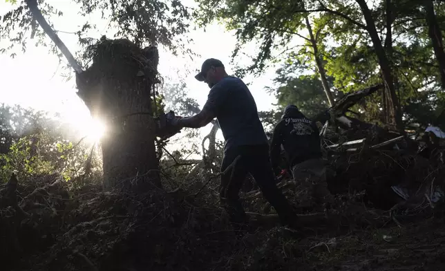 Volunteer Scott Hurt cuts down trees with a coworker as they help carry out search and rescue operations near the Guadalupe River after a flash flood swept through the area, Monday, July 7, 2025, in Ingram, Texas. (AP Photo/Eli Hartman)