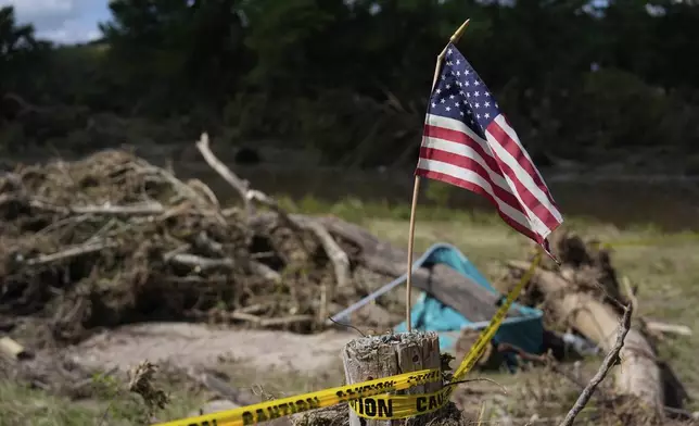 An American flag is placed on a stump in Kerrville, Texas on Tuesday, July 8, 2025. (AP Photo/Ashley Landis)
