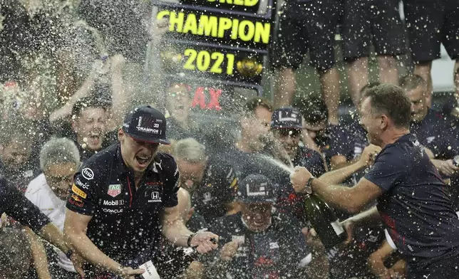 FILE - Red Bull driver Max Verstappen of the Netherlands, left, celebrates with Red Bull team chief Christian Horner, right, and his team in the pit lane after becoming F1 drivers world champion after winning the Formula One Abu Dhabi Grand Prix in Abu Dhabi, United Arab Emirates, Sunday, Dec. 12. 2021. (AP Photo/Kamran Jebreili, File)