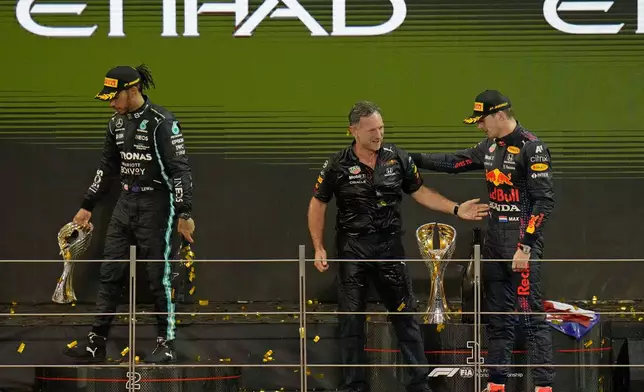 FILE - Red Bull team chief Christian Horner, center, celebrates with his driver Max Verstappen of the Netherlands after winning the Formula One Abu Dhabi Grand Prix in Abu Dhabi, United Arab Emirates, Dec. 12, 2021. Max Verstappen ripped a record eighth title away from Lewis Hamilton, left, with a pass on the final lap of the Abu Dhabi GP to close one of the most thrilling Formula One seasons in years as the first Dutch world champion. (AP Photo/Hassan Ammar, File)