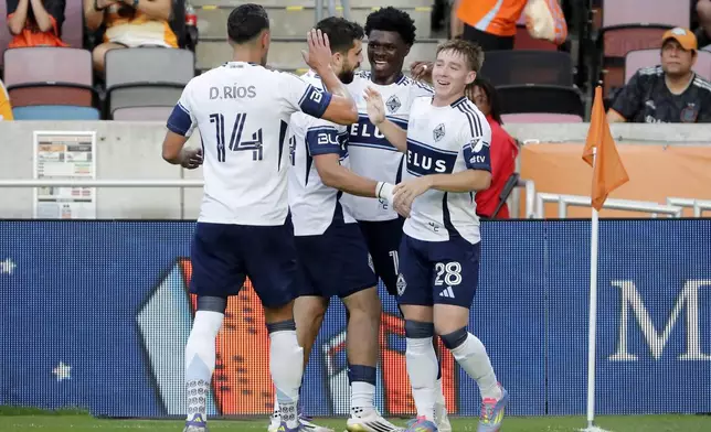 Vancouver Whitecaps, from left, Daniel Ríos (14), Brian White, Emmanuel Sabbi and Tate Johnson celebrate a goal by Sabbi against the Houston Dynamo during the first half of an MLS soccer match, Wednesday, July 16, 2025, in Houston. (AP Photo/Michael Wyke)