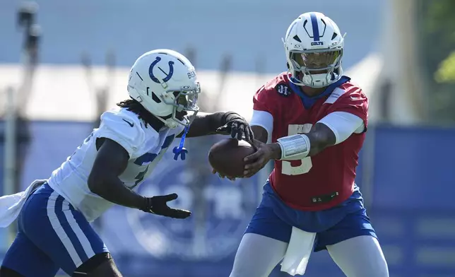 Indianapolis Colts quarterback Anthony Richardson Sr. (5) hands off to running back Ulysses Bentley IV (37) during practice at the NFL football team's training camp in Westfield, Ind., Wednesday, July 23, 2025. (AP Photo/Michael Conroy)