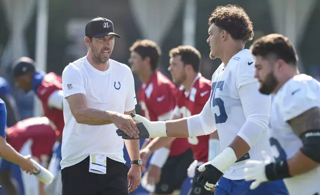 Indianapolis Colts head coach Shane Steichen greets tackle Jalen Travis (75) during practice at the NFL football team's training camp in Westfield, Ind., Wednesday, July 23, 2025. (AP Photo/Michael Conroy)