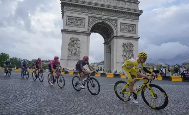 The pack with Slovenia's Tadej Pogacar, wearing the overall leader's yellow jersey, passes the Arc de Triomphe during the twenty-first stage of the Tour de France cycling race over 132.3 kilometers (82.1 miles) with start in Mantes-la-Ville and finish on the Champs-Elysees in Paris, France, Sunday, July 27, 2025. (AP Photo/Mosa'ab Elshamy)