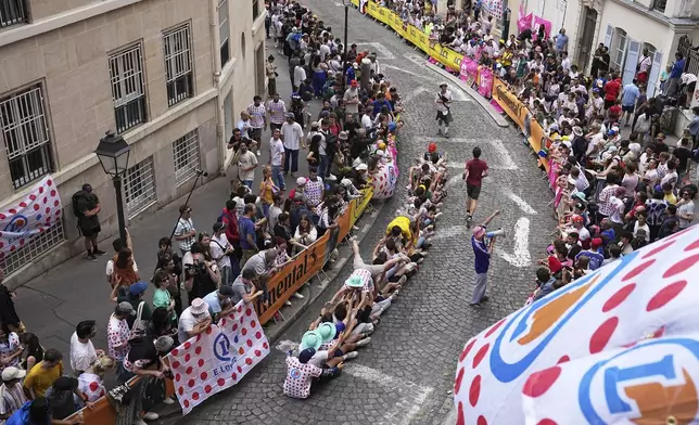 Cycling fans have fun on the street in the Montmartre district before the last stage of the Tour de France cycling race between Mantes-la-Ville and Paris, Sunday, July 27, 2025 in Paris (AP Photo/Laurent Cipriani)