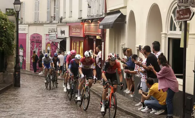 The pack rides to at the Place de Tertre in the Montmartre district, during the last stage of the Tour de France cycling race between Mantes-la-Ville and Paris, Sunday, July 27, 2025 in Paris (AP Photo/Thomas Padilla)