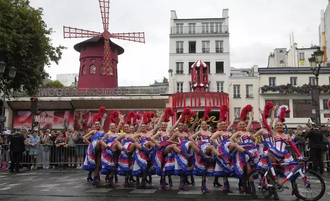 Dancers perform the Cancan dance outside the Moulin Rouge cabaret during the last stage of the Tour de France cycling race between Mantes-la-Ville and Paris, Sunday, July 27, 2025 in Paris (AP Photo/Michel Euler)