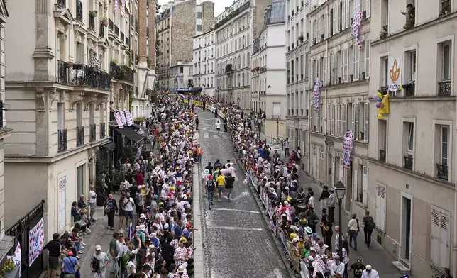 Cycling fans run on the street in the Montmartre district before the last stage of the Tour de France cycling race between Mantes-la-Ville and Paris, Sunday, July 27, 2025 in Paris (AP Photo/Laurent Cipriani)