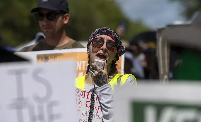 Protesters march outside the Dade-Collier Training and Transition Airport where President Donald Trump appeared, Tuesday, July 1, 2025, in Ochopee, Fla. (AP Photo/Michael Laughlin)