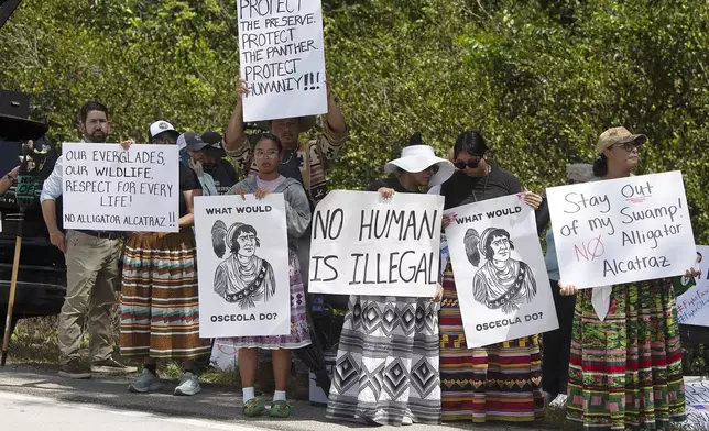 Protesters march outside the Dade-Collier Training and Transition Airport where President Donald Trump appeared, Tuesday, July 1, 2025, in Ochopee, Fla. (AP Photo/Michael Laughlin)