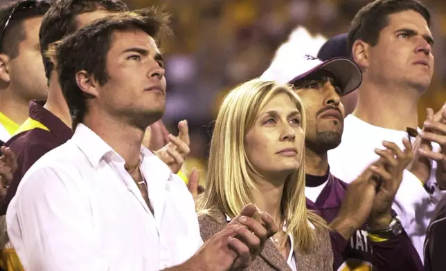 FILE - Former Arizona State player Pat Tillman's wife Marie Tillman, center, and his brother Richard Tillman, left, applaud as they watch Pat's name and jersey number enshrined in the university's ring of honor during halftime ceremonies between Washington State and Arizona State, Nov. 13, 2004, in Tempe, Ariz. (AP Photo/Paul Connors, File)