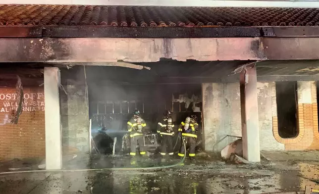 This photo provided by the San Jose Fire Department shows firefighters responding to a fire burning after a car crashed into a Post Office, early Sunday, July 20, 2025, in San Jose, Calif. (San Jose Fire Department via AP)