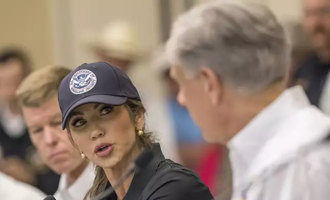 CORRECTS TO KERRVILLE, NOT INGRAM - Homeland Security Secretary Kristi Noem, center, speaks with Texas Gov. Greg Abbott, right, about ongoing search and rescue efforts after recent flooding along the Guadalupe River during a press conference on Saturday, July 5, 2025, in Kerrville, Texas. (AP Photo/Rodolfo Gonzalez)
