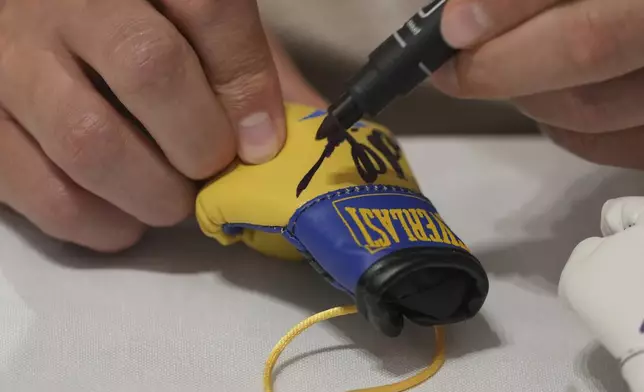 Ukraine's boxer Oleksandr Usyk signs autograph as he meets the Ukrainian war veterans, who are employees of Ukrainian power company DTEK at a hotel in Battersea Park in London, Thursday, July 17, 2025 ahead of the undisputed heavyweight champion boxing fight between Britain's Daniel Dubois and Oleksandr Usyk on Saturday. (AP Photo/Kin Cheung)