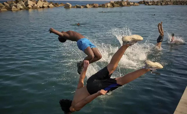Men jump into the water on a hot day in Barcelona, Spain, Tuesday, July 1, 2025. (AP Photo/Emilio Morenatti)