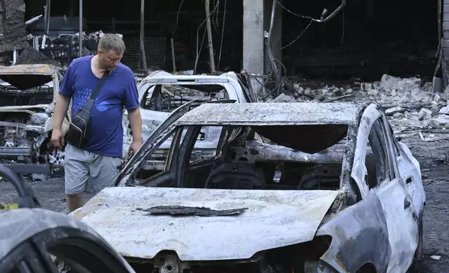 A resident looks at damaged cars at a residential area following Russia's drone attack in Odesa, Ukraine, Tuesday, July 22, 2025. (AP Photo/Michael Shtekel)
