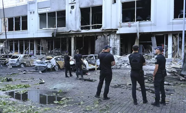 Police officers inspect damaged cars at a residential area following Russia's drone attack in Odesa, Ukraine, Tuesday, July 22, 2025. (AP Photo/Michael Shtekel)