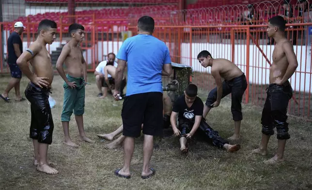 Young wrestlers prepare as they wait for their turn to compete during the 664th annual Historic Kirkpinar Oil Wrestling Championship, in Edirne, northwestern Turkey, Sunday, July 6, 2025. (AP Photo/Khalil Hamra)