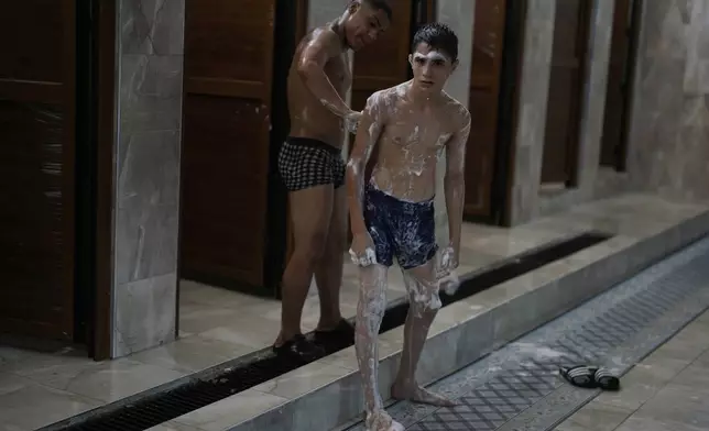 Young wrestlers try to recover on the shower room after they competed on the last day of the 664th annual Historic Kirkpinar Oil Wrestling championship, in Edirne, northwestern Turkey, Sunday, July 6, 2025.(AP Photo/Khalil Hamra)