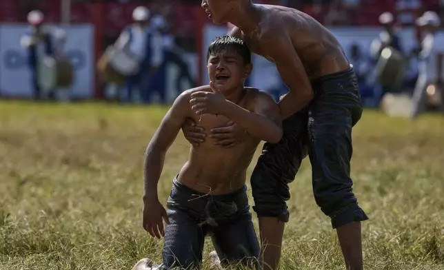 A young wrestler reacts after losing in a round during the 664th annual Historic Kirkpinar Oil Wrestling championship, in Edirne, northwestern Turkey, Sunday, July 6, 2025.(AP Photo/Khalil Hamra)