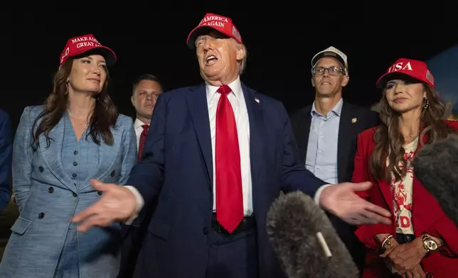 President Donald Trump, center, speaks with reporters as, from left, Agriculture Secretary Brooke Rollins, Rep. Zachary Nunn, R-Iowa, Rep. Randy Feenstra, R-Iowa, and Homeland Security Secretary Kristi Noem listen as they arrive on Air Force One, Friday, July 4, 2025, at Joint Base Andrews, Md. (AP Photo/Alex Brandon)